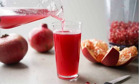 Fresh pomegranate juice being poured into a glass