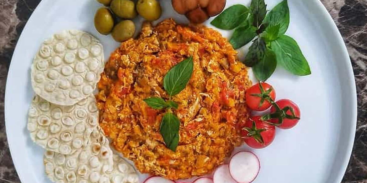 Mirza Ghasemi served with crisp flatbread, tomatoes, radishes, olives and fresh herbs